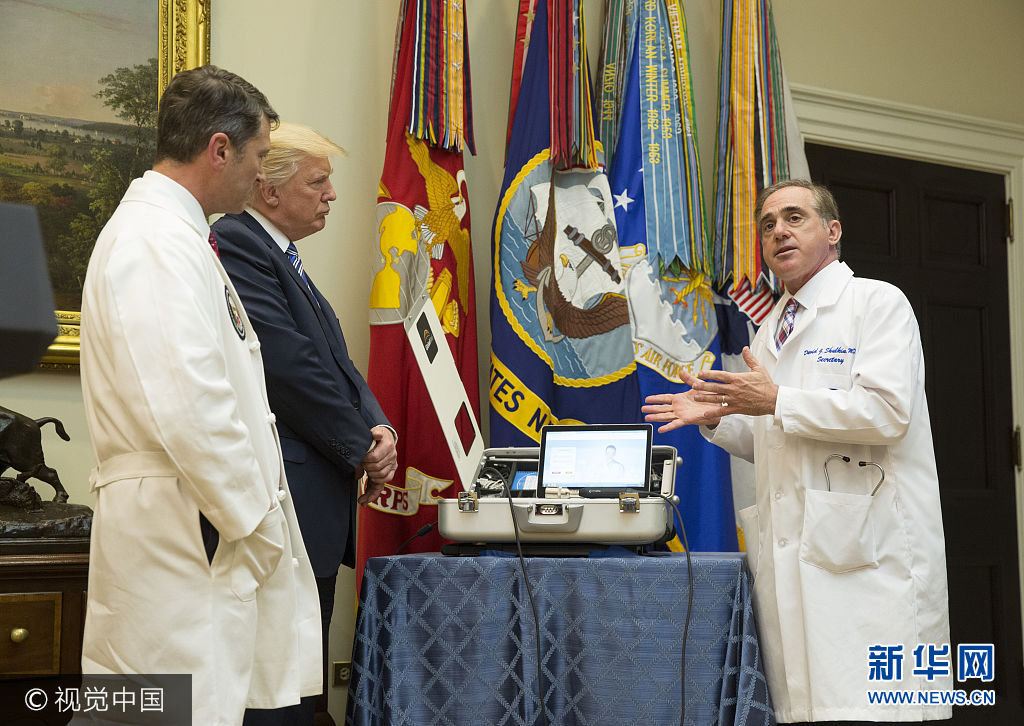 当地时间2017年8月3日，美国华盛顿，美国总统特朗普参观退伍军人事务部，与退伍军人事务部部长大卫·舒尔金共同见证使用视频和软件科技为退伍军人提供医疗帮助的新项目。***_***WASHINGTON, DC - AUGUST 3: (AFP OUT) U.S. Veterans Affairs Secretary Dr.David Shulkin(right) explains equipment to White House Physician Dr. Ronny L. Jackson(left) U.S. President Donald Trump (2nd left) to be used in a new program using video and software technology to provide medical care to veterans at The White House August 3, 2017 in Washington, DC.  (Photo by Chris Kleponis-Pool/Getty Images)