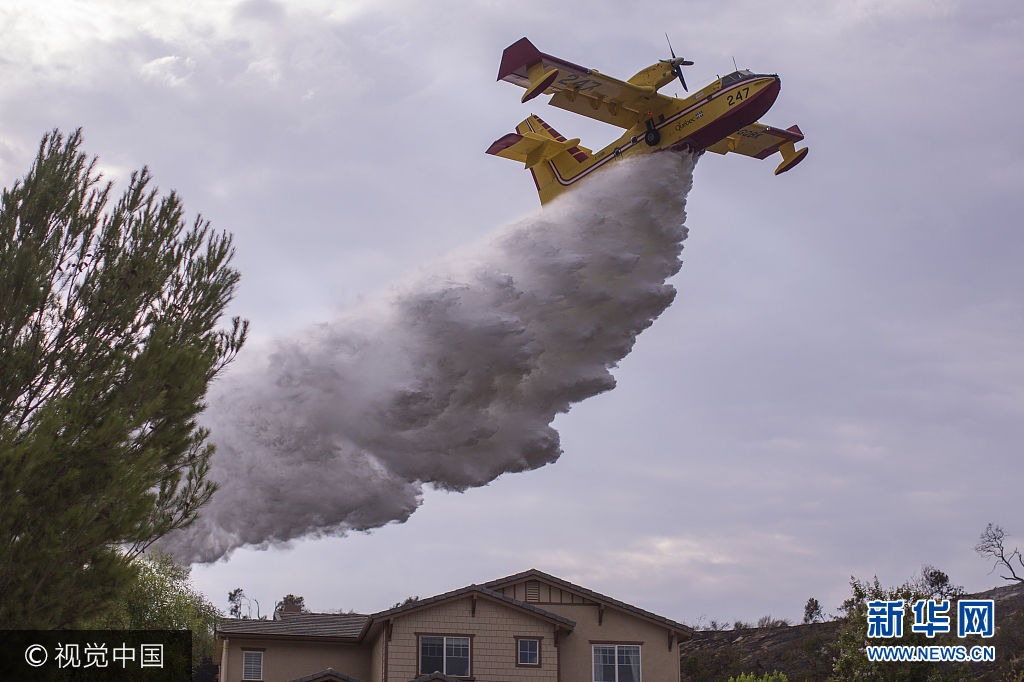 当地时间2017年9月3日，美国加州伯班克，拉图纳峡谷发生山火，过火面积近24平方公里，目前只控制住10%的火势。***_***BURBANK, CA - SEPTEMBER 03: A Super Scooper CL-415 firefighting aircraft from Canada makes a drop to protect a house during the La Tuna Fire on September 3, 2017 near Burbank, California. At nearly 6,000 acres, the fire is the biggest fire in terms of acreage in Los Angeles city history. About 100 Los Angles firefighters are expected to return soon from Texas, where they've been helping survivors from Hurricane Harvey.    (Photo by David McNew/Getty Images)