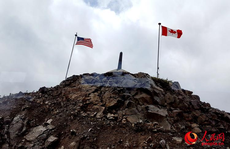 在克朗代克山峰最高处耸立着美加国界碑，两侧分别是美加国旗  于世文  摄 